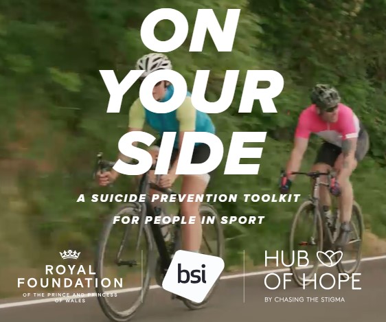 Promotional graphic for a suicide prevention resource aimed at people involved in sport. The image shows two cyclists riding on a road with trees and greenery in the background. Large white text reads: “ON YOUR SIDE” followed by “A Suicide Prevention Toolkit for People in Sport.” Logos for Royal Foundation, BSI, and Hub of Hope appear at the bottom of the image. The design highlights support and suicide prevention for those participating in sport and physical activity.